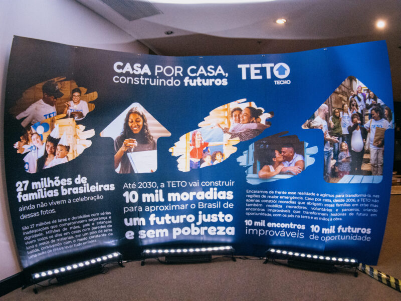 Painel grande com imagens da organização e dados sobre moradia no Brasil.
