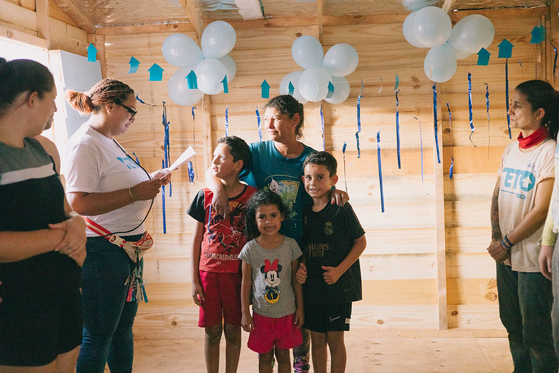 Família rcelebra casa construída ao lado de voluntários da TETO