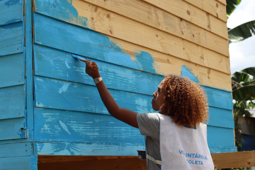 Voluntária pintando moradia construída pela TETO Brasil durante ação em território.