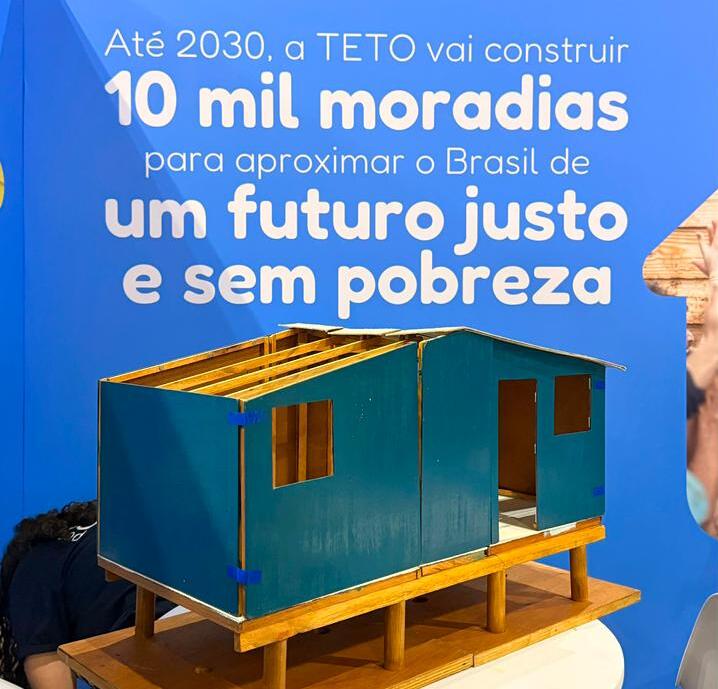 Maquete de uma das moradias construídas pela TETO Brasil em exibição no estande da organização durante o Web Summit Rio 2026. O modelo ilustra o padrão de habitação digna, segura e com resiliência climática que a TETO busca garantir para comunidades vulneráveis.